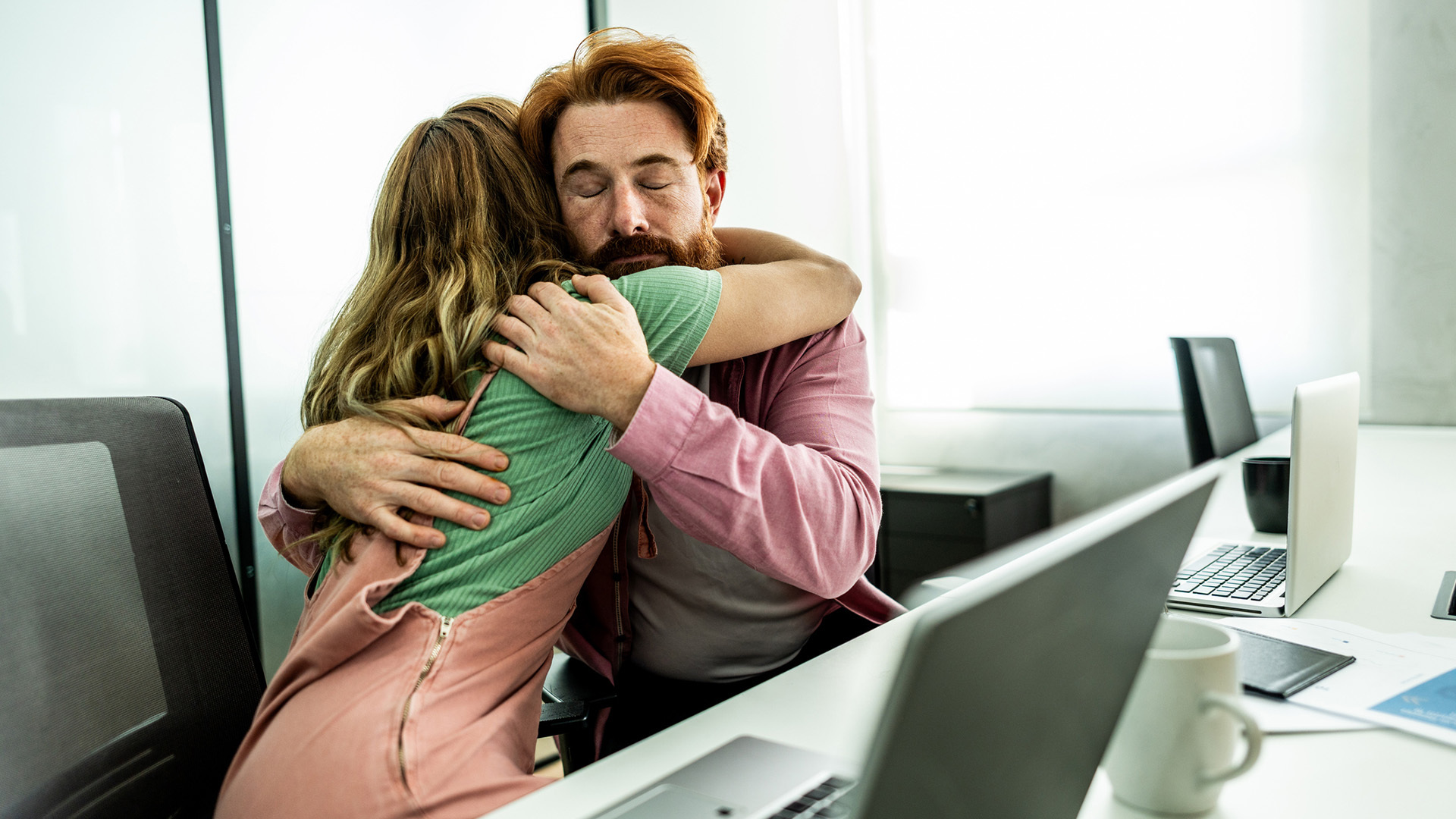 Två personer som kramas vid ett kontorsbord