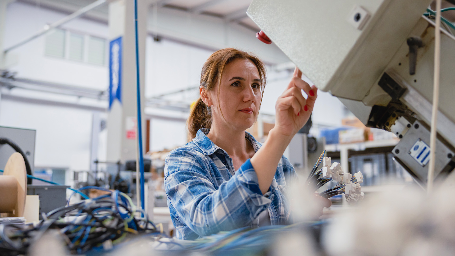 Kvinnlig industriarbetare som arbetar med tillverkningsutrustning i en fabrik