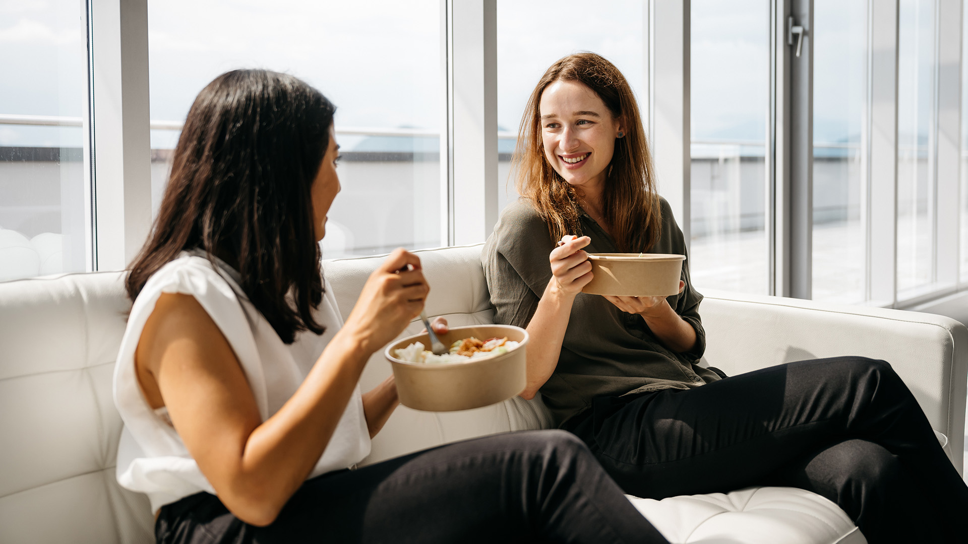 Två affärskvinnor som äter hälsosam lunch på jobbet